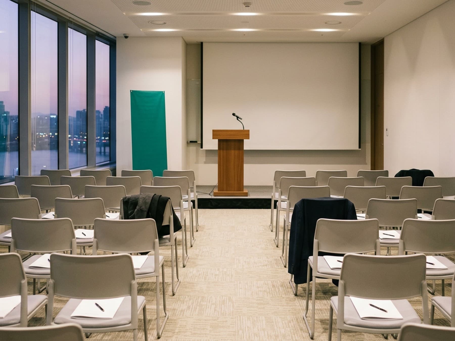 Evening investor seminar with an audience watching a presenter standing beside a screen
